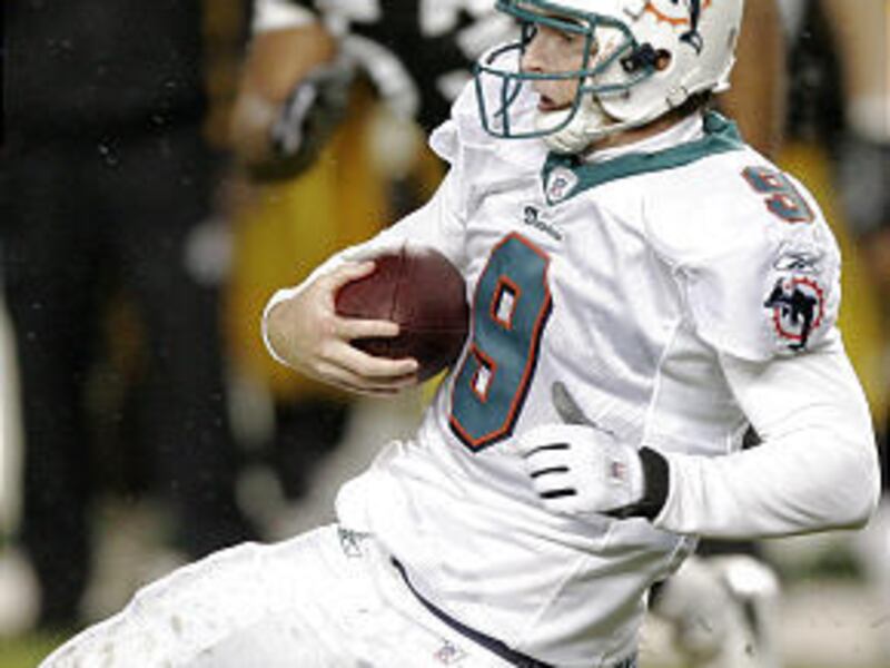 Miami Dolphins rookie quarterback John Beck slides on sloppy field as he scrambles for a first down against Steelers.