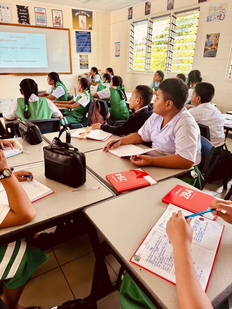 Children in a classroom in Tonga participate in a lesson about human rights in 2025.