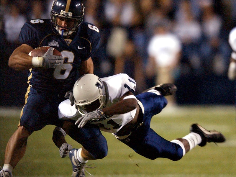 BYU’s Luke Staley gets knocked out of bounds by Utah State’s Donta’ Carter during a game at LaVell Edwards Stadium in 2001.