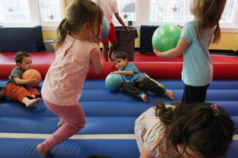 Dashiell Kwan, 3, seated center, holds a ball as he and other children participate in a gymnastics class in New York, Tuesday, May 27, 2008.
