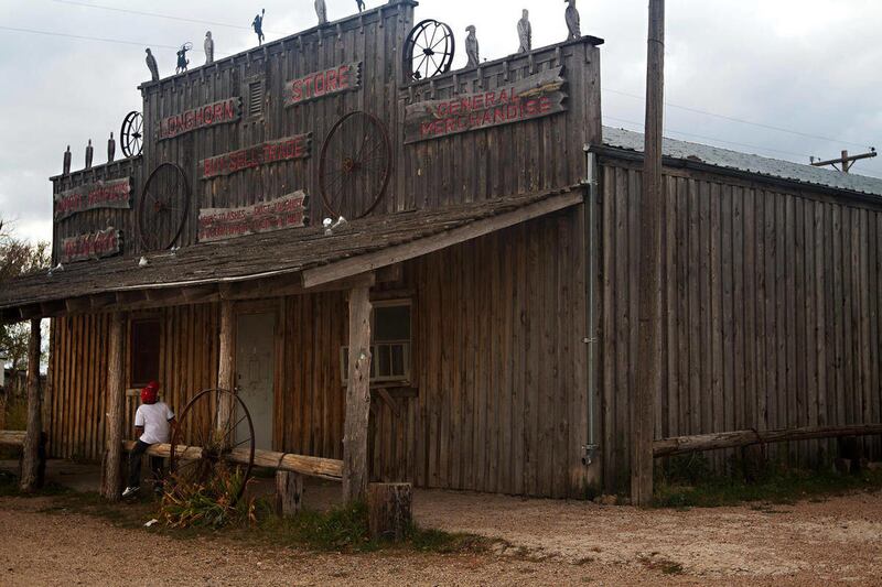 In this Oct. 6, 2011 photo, a person sits outside of the Longhorn Store in Scenic, S.D. While never a booming metropolis, Scenic once boasted a saloon, three gas stations, a dance hall and a school. Today, just one business remains: the U.S. Post Office.