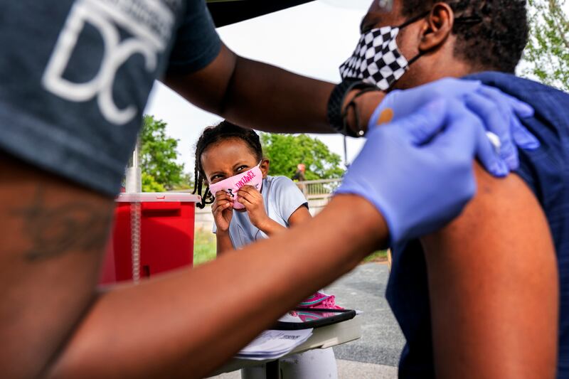 Heran Abebe, 6, reacts as she watches her father Alebel Belay receive a Johnson & Johnson COVID-19 vaccine shot in May at The REACH at the Kennedy Center in Washington.