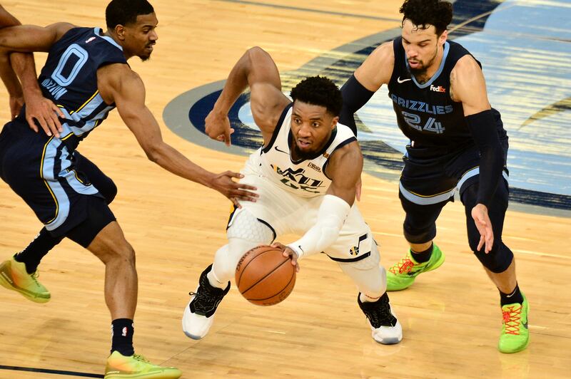 Utah Jazz guard Donovan Mitchell dribbles between Memphis Grizzlies defenders De’Anthony Melton (0) and Dillon Brooks.