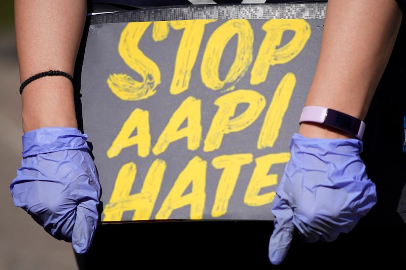 A woman holds a sign and attends a rally to support stopping AAPI (Asian Americans and Pacific Islanders) hate.