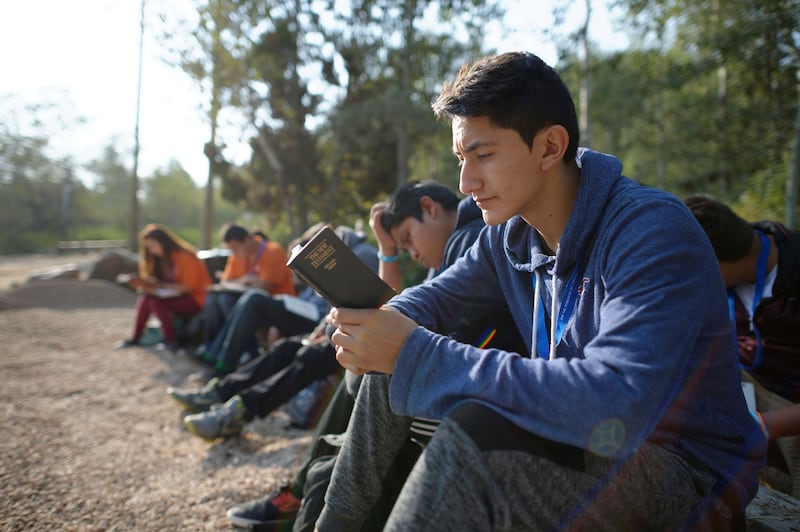 A group of youth read while sitting outdoors.