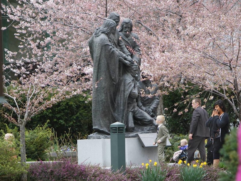 A young family looks at a statue of the Melchizedek Priesthood restoration on Temple Square.