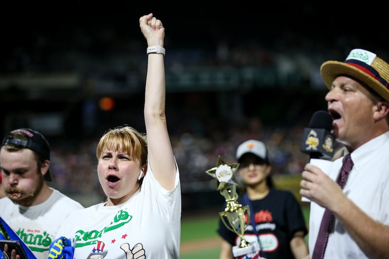 Katie Prettyman, of Marysville, Wash., celebrates her win in the women's division of a Nathan's Famous qualifier hot dog-eating contest, having eaten 14 hot dogs, at Smith's Ballpark in Salt Lake City on Tuesday, July 23, 2019. The top male and female fin