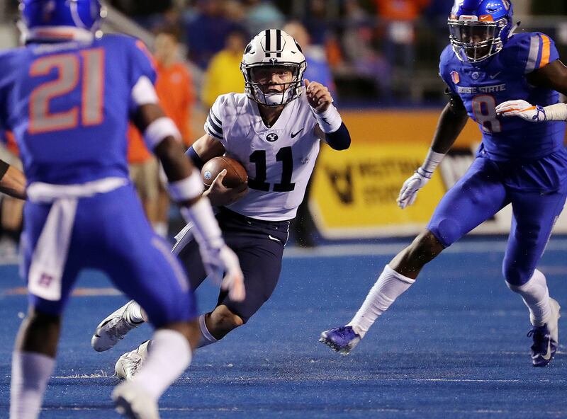 Brigham Young Cougars quarterback Zach Wilson runs the ball against Boise State Broncos safety Tyreque Jones and linebacker Jabril Frazier during NCAA football in Boise on Saturday, Nov. 3, 2018.