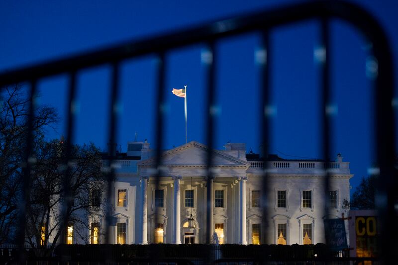 The White House is seen through a security fence, before sunrise, in Washington.