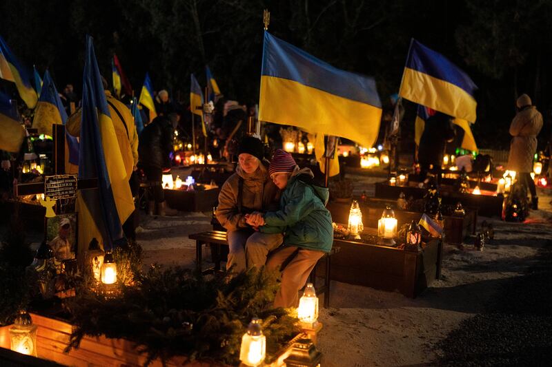 41 year-old Olesia and her 8 year-old daughter Uliana sits next to the grave of her husband Ihor Marchenko at Lviv cemetery, western Ukraine.