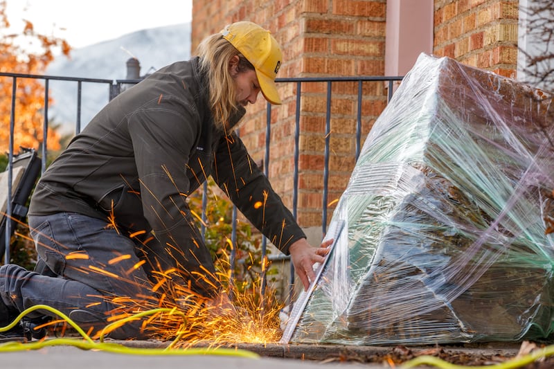 Sparks fly as an art handler works to free a 2,500-pound petroglyph rock in concrete, on Monday, December 8, 2025, in Tremonton, Utah.