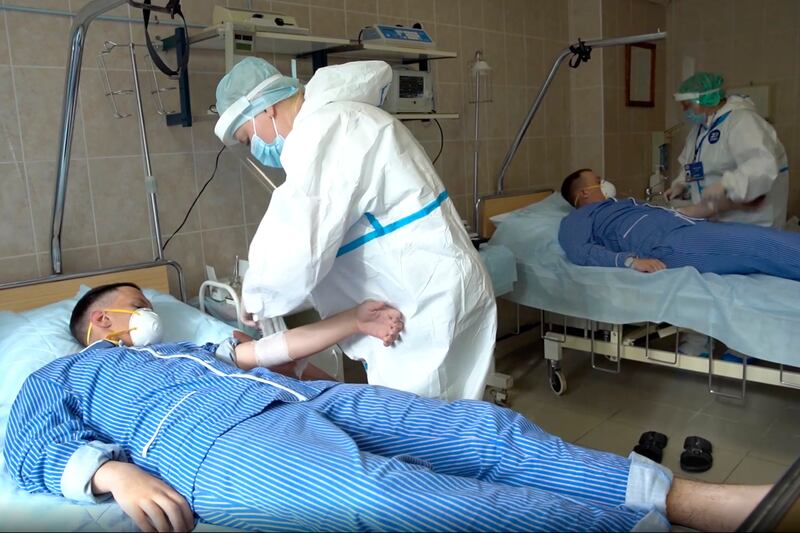 In this file photo made from footage provided by the Russian Defense Ministry on Wednesday, July 15, 2020, medical workers in protective gear prepare to draw blood from volunteers participating in a trial of a coronavirus vaccine at the Budenko Main Military Hospital outside Moscow, Russia.