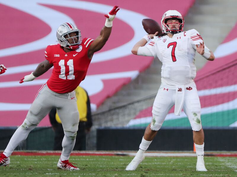 Utah Utes quarterback Cameron Rising, wearing white, throws.