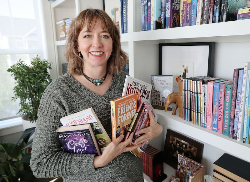 Shannon Hale holds some of the books she has written at her home in South Jordan, Utah.