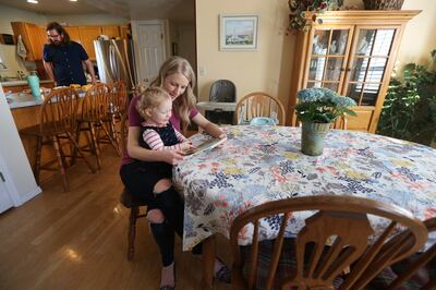Tara reads to their daughter Sage while Steven finishes preparing dinner as the Minert family spends time at home on Monday, March 5, 2018.