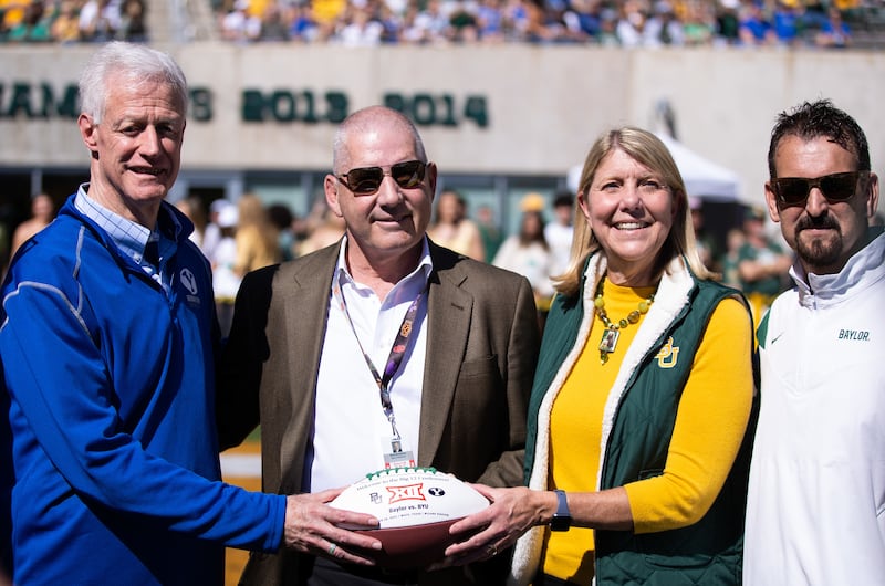 BYU President Kevin Worthen, left, accepts a game ball from Baylor University President Linda Livingstone on Oct. 16, 2021.