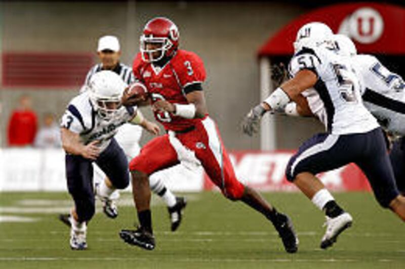 Utah quarterback Brian Johnson skirts between Utah State players