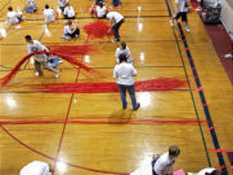 Students at Eisenhower Junior High try to set a record for the world's longest straw chain by linking together more than four miles of drinking straws in the school gym.
