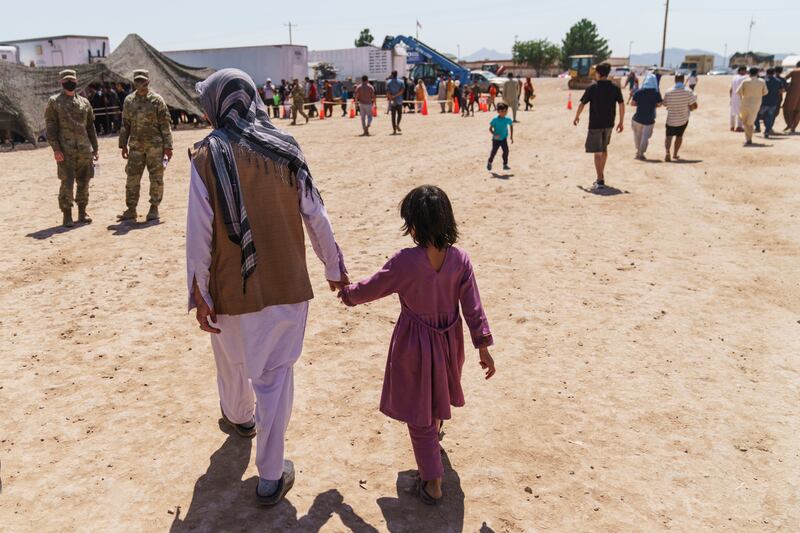 A man walks with a child through Fort Bliss’ Doña Ana Village where Afghan refugees are being housed.