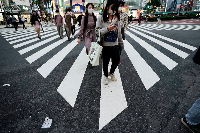 People wearing protective masks to help curb the spread of the coronavirus walk at a a pedestrian crossing Thursday, Oct. 15, 2020, in Tokyo. The Japanese capital confirmed more than 280 new coronavirus cases on Thursday.