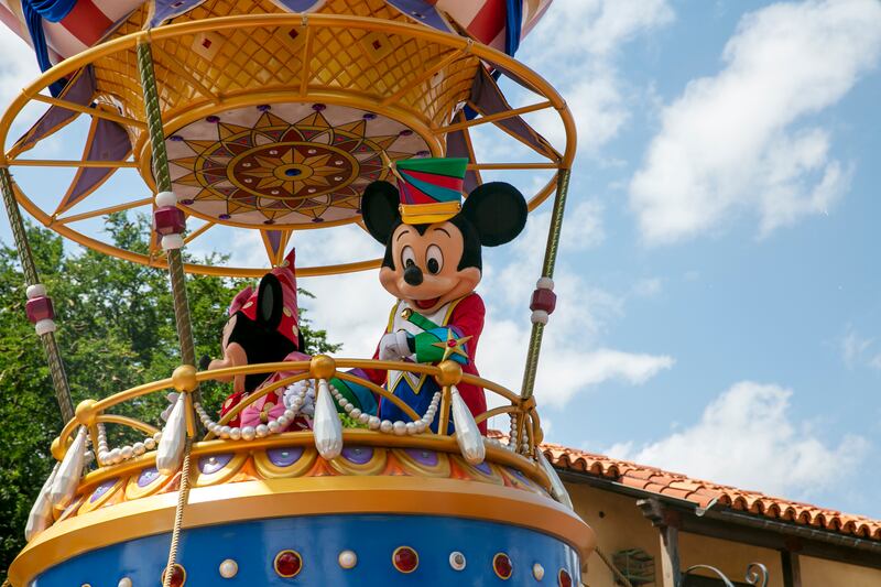 Actors portraying Mickey Mouse and Minnie Mouse wave to visitors during a parade at Walt Disney World Resort.