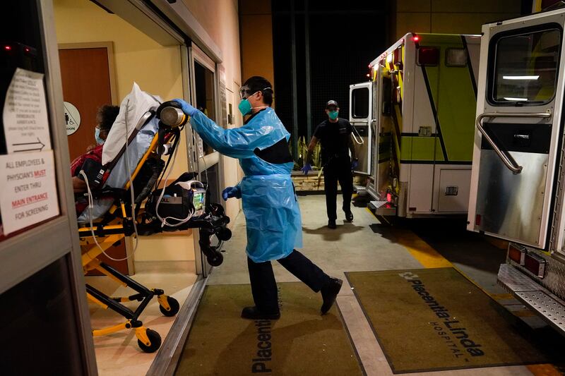 An emergency medical technician pushes a gurney into an emergency room.