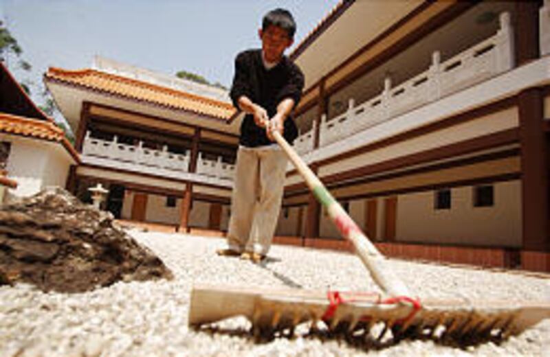 A volunteer rakes a gravel garden at the Zu Lai Buddhist temple in Cotia, Brazil. The complex also includes a monastery.