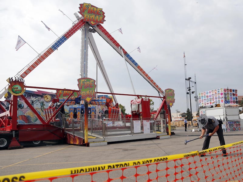 An Ohio State Highway Patrol trooper removes a ground spike from in front of the fire ball ride at the Ohio State Fair Thursday, July 27, 2017, in Columbus, Ohio.  The fair opened Thursday but its amusement rides remained closed one day after Tyler Jarrel