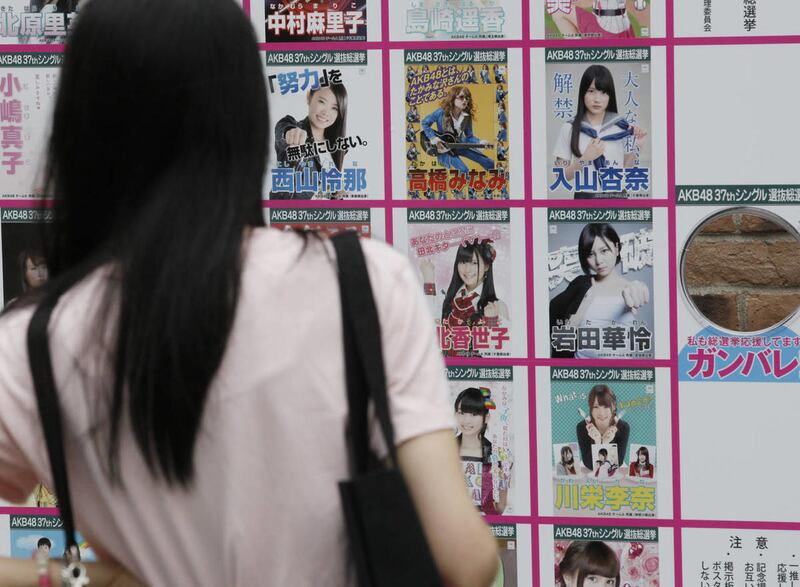 A woman looks at the pictures of AKB48 members at AKB48 cafe and shop at Akihabara district in Tokyo, Monday, May 26, 2014. Two members of the all-female Japanese pop group AKB48 and one staffer have been injured by a saw-wielding man at a fan event.