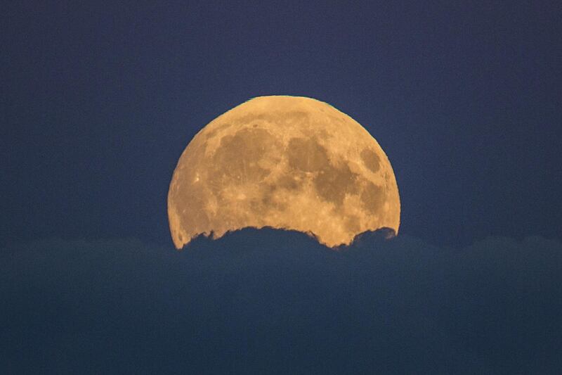 A full moon rises between clouds in Berlin, Germany, Sunday, Sept. 27, 2015.