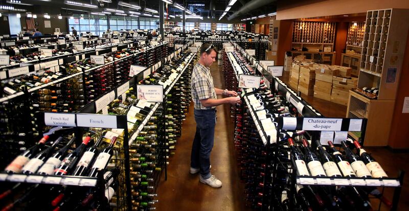 FILE - In this June 30, 2017, file photo, a worker at a state liquor store changes prices on wine, liquor and beer in Salt Lake City. Selection, beer and cold were among the words state-run liquor store customers used most in the Utah Department of Alcoho