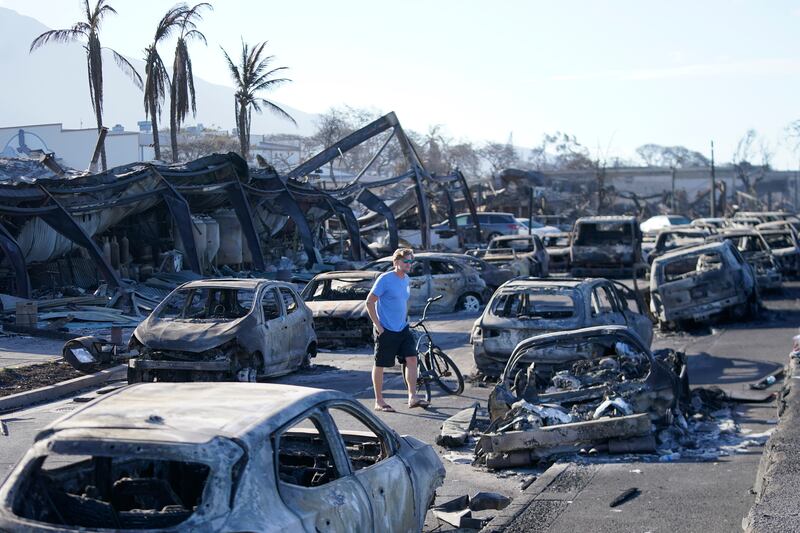 A man walks through wildfire wreckage in Lahaina, Hawaii.