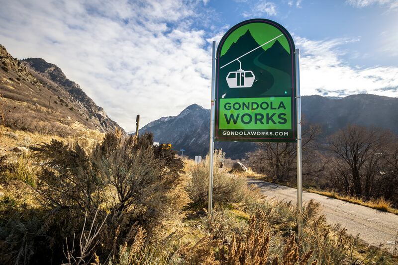 A green sign reading “Gondola Works” stands at the base of Little Cottonwood Canyon.