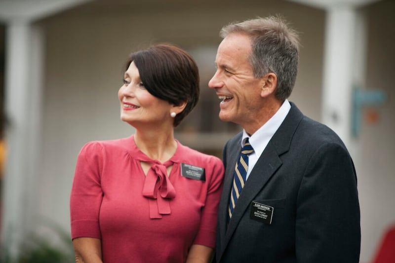 A senior missionary couple stands and smiles.