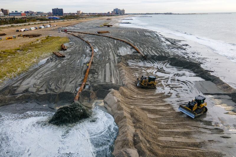 Contractors for the U.S. Army Corps of Engineers pump sand from the ocean floor onto the beach in New York City.