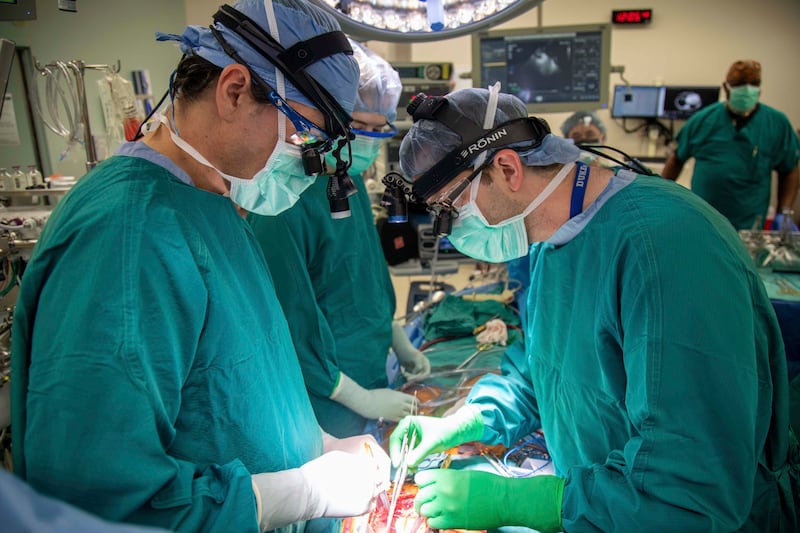 In this photo provided by Duke Health, surgeons Dr. Jacob Schroder, left, and Dr. Zachary Fitch perform a heart transplant.