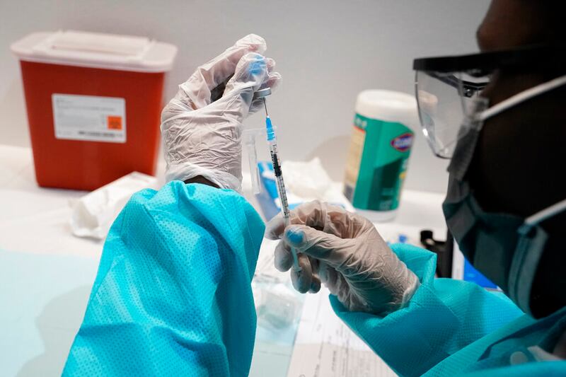 A health care worker fills a syringe with the Pfizer COVID-19 vaccine.