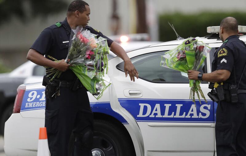 A Dallas police officer handles flowers they received at a roadblock outside their headquarters, Saturday, July 9, 2016, in Dallas. A peaceful protest, over the recent shootings of black men by police, turned violent Thursday night as gunman Micah Johnson