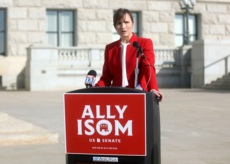 Ally Isom wearing a red blazer stands in front of the Utah State Capitol building and speaks.