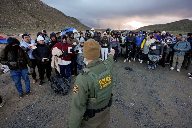 A Border Patrol agent asks asylum-seeking migrants to line up near Jacumba Hot Springs, Calif.