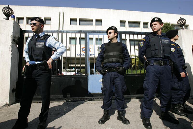 Police stand outside a state vocational training college in western Athens, Greece, where a 18-year-old student shot and injured a fellow student and two passers-by before fatally shooting himself in the head, Friday.