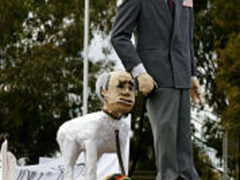 Peace activists hold aloft effigies of President George Bush followed by a dog depicted with the head of Australian Prime Minister John Howard onto the lawn of Parliament House in Canberra to protest the president's visit.