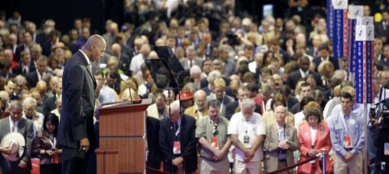 Former NBA player Thurl Bailey, at the podium, leads the invocation at the opening session of the Republican National Convention in St. Paul, Minn., today.