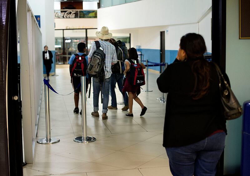 Maria Santiago watches her two oldest children, Patrick and Sarai, and their chaperones, Easton Smith and Kate Savage, head to security at La Aurora International Airport in Guatemala City on Wednesday, Oct. 17, 2018.