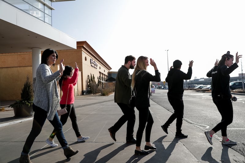 Shoppers evacuate with their hands in the air after a shooting at Fashion Place Mall in Murray on Sunday, Jan. 13, 2019.
