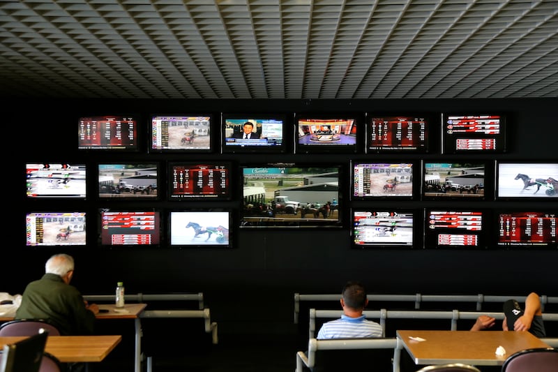 Men watch horse racing on an array of screen at Monmouth Park Racetrack in Oceanport, N.J., Monday, May 14, 2018. The Supreme Court on Monday gave its go-ahead for states to allow gambling on sports across the nation, striking down a federal law that barr