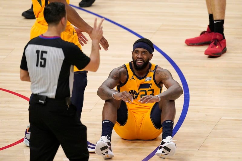 Utah Jazz forward Royce O’Neale, right, sits on the floor after committing a foul.