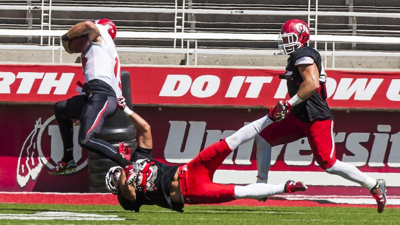 Utah quarterback Chase Hansen gets tackled by defensive back Austin Lee during a scrimmage at the Rice-Eccles Stadium in Salt Lake City on Thursday, Aug. 13, 2015.