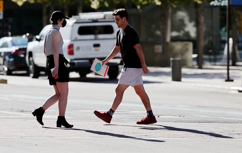 Two pedestrians — one with a mask and the other without — pass each other in Salt Lake City.