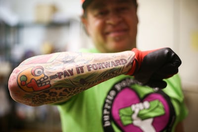 Jorge Fierro, owner of Rico Brand, displays his tattoo reading "pay it forward" the company's headquarters in Salt Lake City on Thursday, March 7, 2019. Four nights each week, Rico donates 200 to 300 to be given to the homeless as part of the Burrito Proj